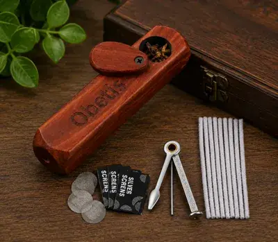 Rosewood pocket pipe with its swivel lid open, beside a cleaning tool and steel screens